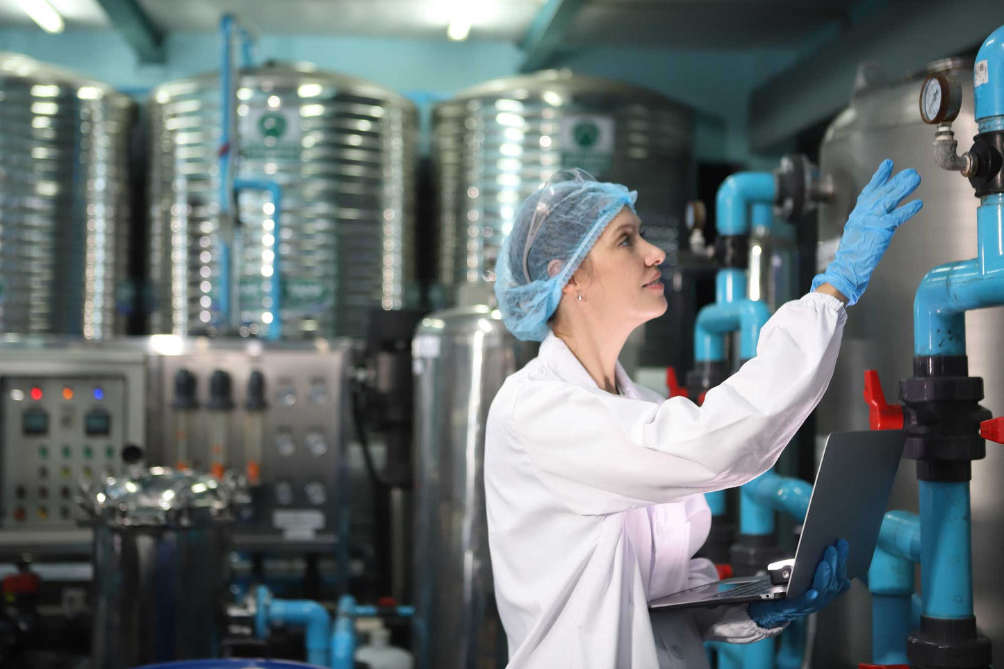 Woman in water treatment plant checking a valve. 
