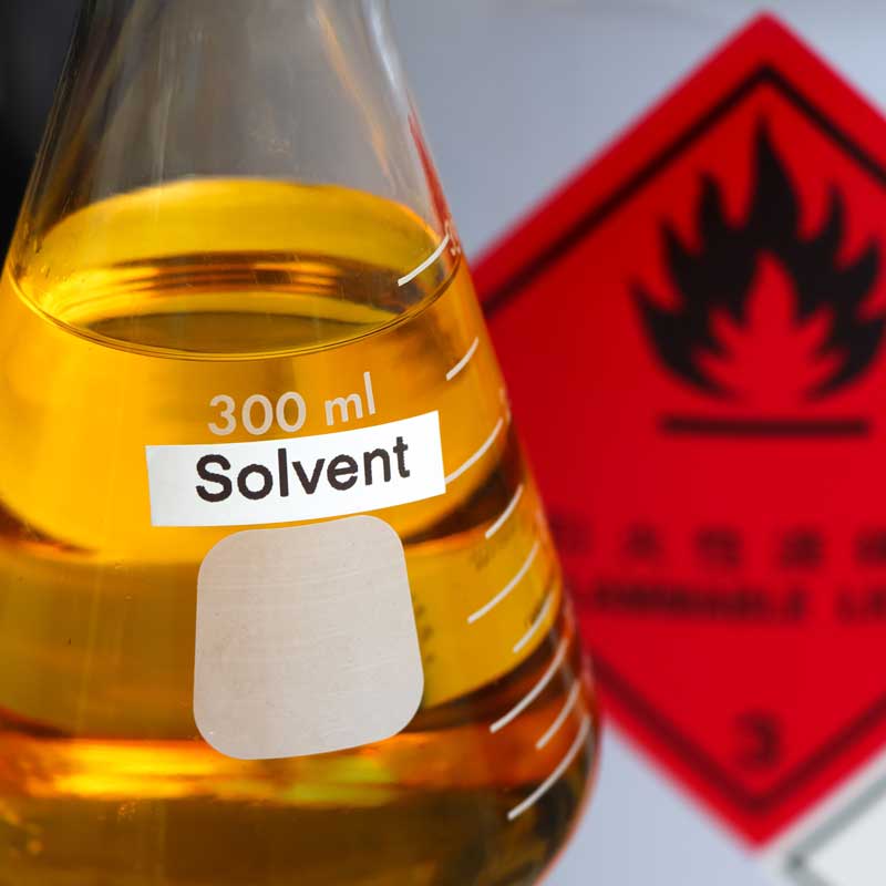 300 ml Solvent labeled beaker with a warning sign in the background