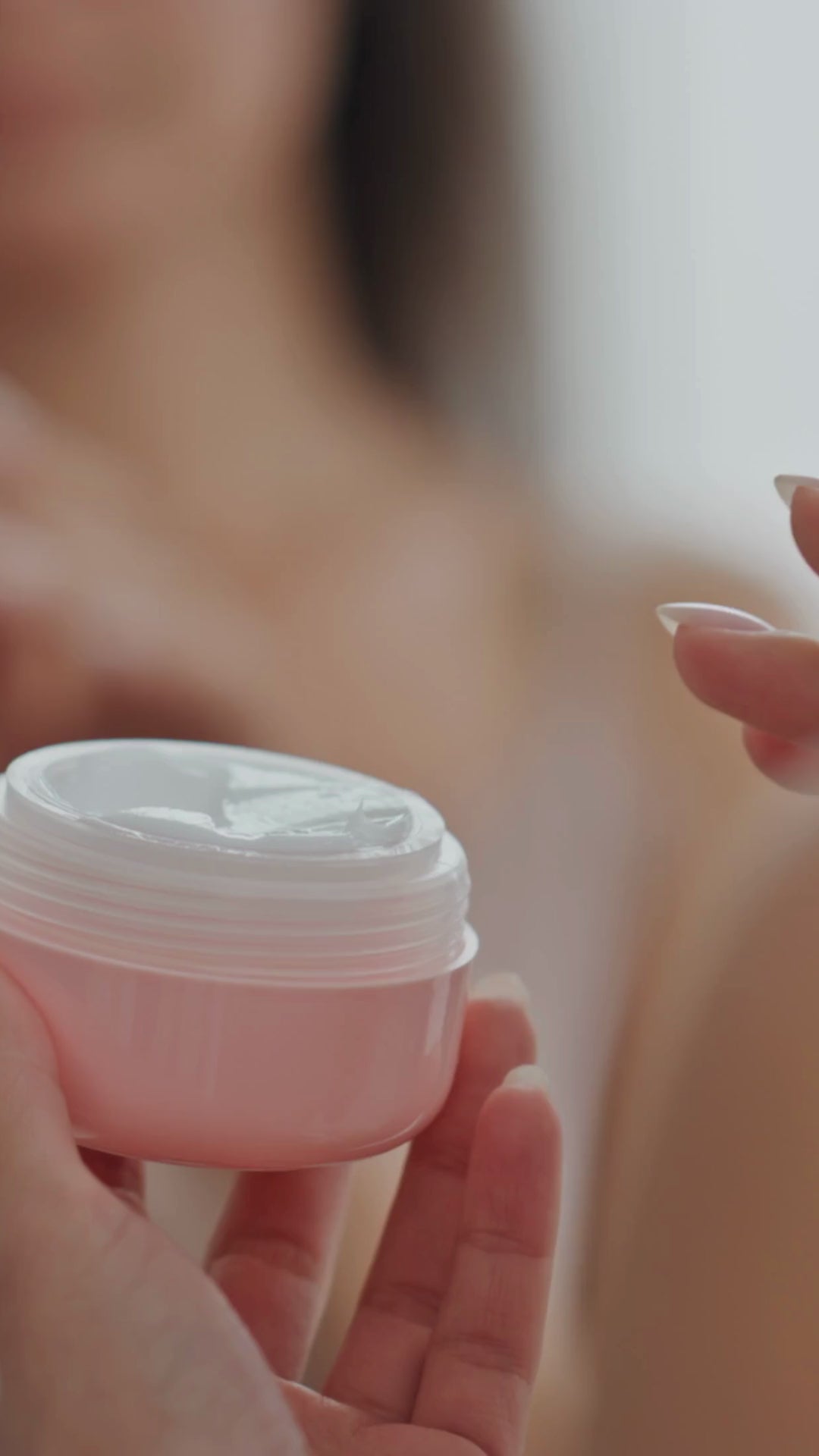 Woman using moisturizer made with Glycerin from a container.