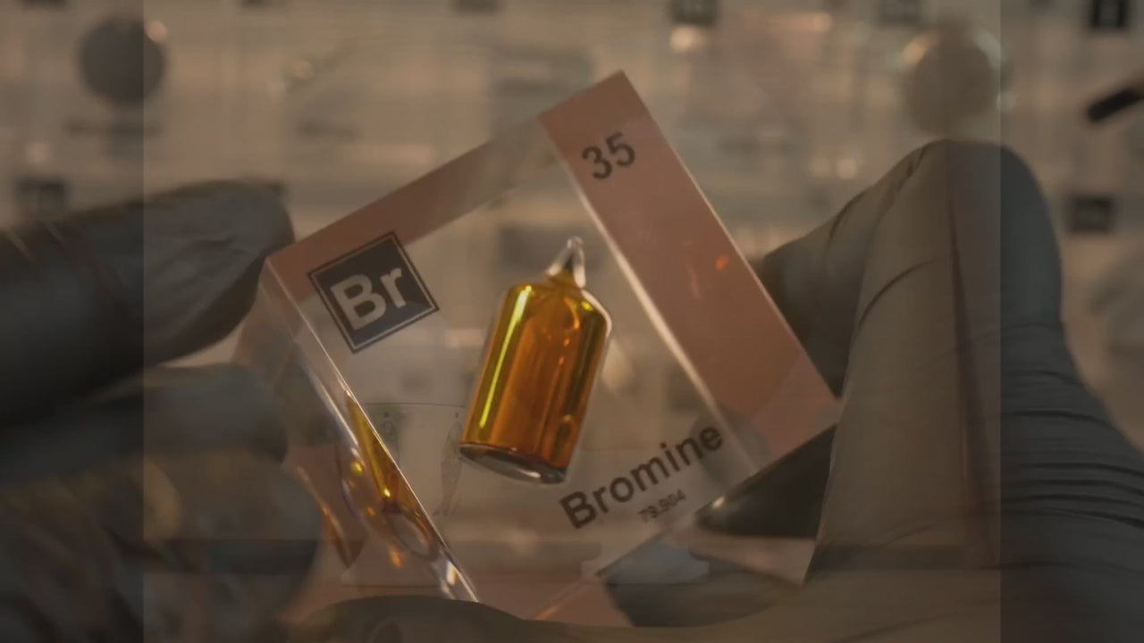 Sample of Bromine in a tube encased in a clear plastic cube with periodic element labeling.
